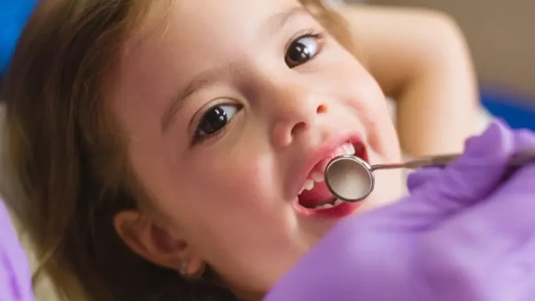 A child calmly having her teeth examined.